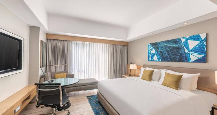 Helles Hotelzimmer mit moderner Einrichtung und großen Fenstern.