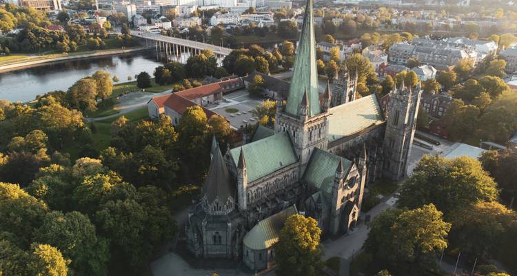 Aerial view of Trondheim’s gothic Nidaros Cathedral surrounded by green parks and the city river.