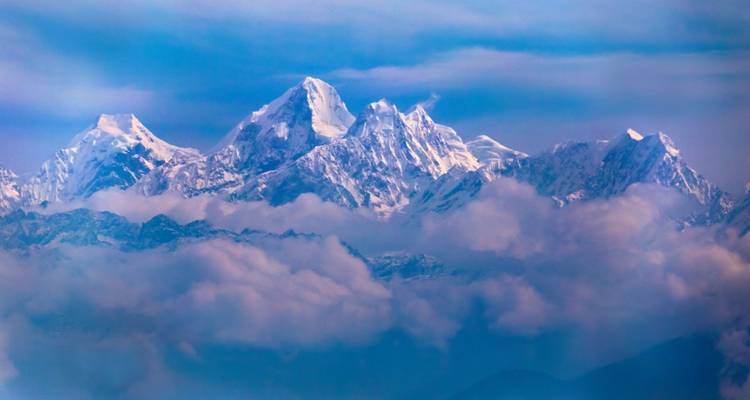 Montagnes enneigées avec des nuages sous les sommets.