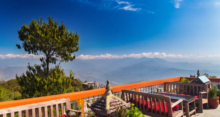 Terrasse avec sièges en bois donnant sur un paysage montagneux.