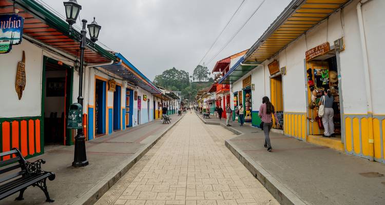 Calle peatonal bordeada de edificios de colores vivos y algunos locales caminando por el tranquilo centro del pueblo.