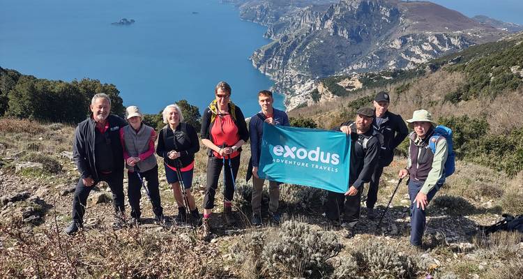 Un grupo de personas con una pancarta de 'exodus adventure travels' en un sendero de senderismo en Italia.
