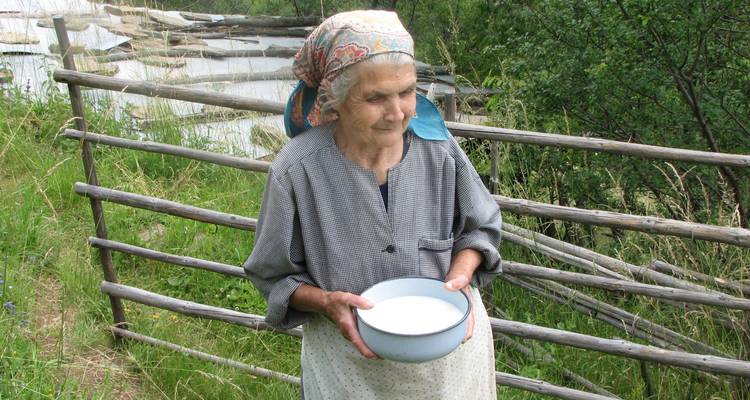 Femme âgée tenant un bol dans un environnement rural.