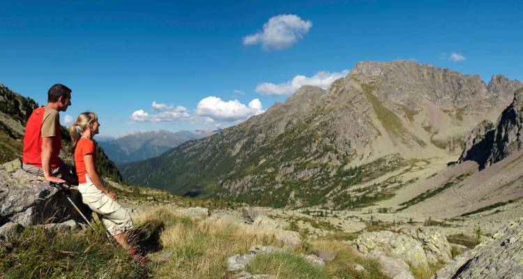 Two people admiring a valley view from a rocky perch.