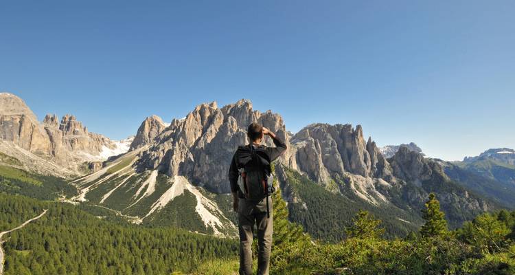 Persona de pie en una colina con vistas a picos y valles montañosos.