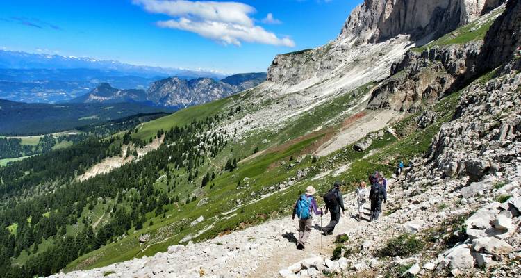 Hikers descending down a rocky mountain landscape.