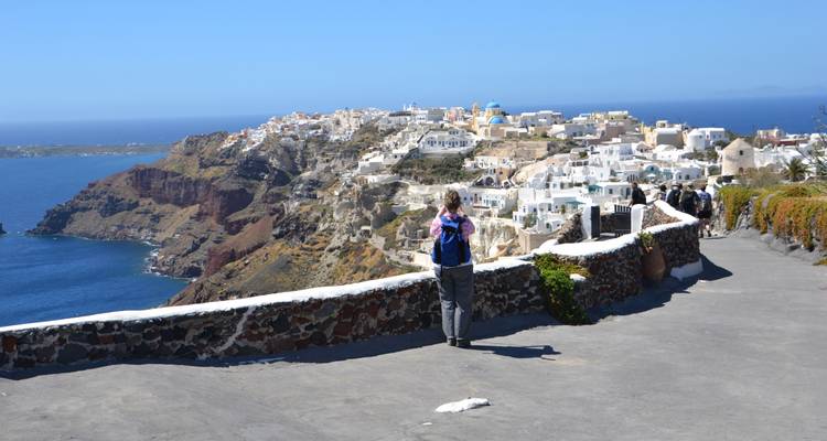Persona de pie en un camino con vistas a una ciudad costera y al mar.