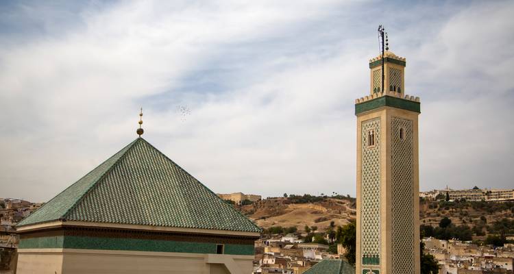 Islamic architecture with a green-tiled minaret in Fes.