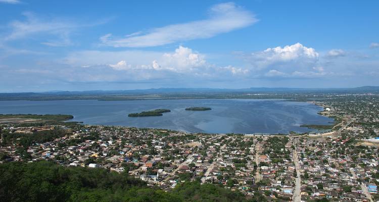 Vue aérienne d'un lagon côtier avec de petites îles et la ville environnante sous un ciel bleu éclatant.