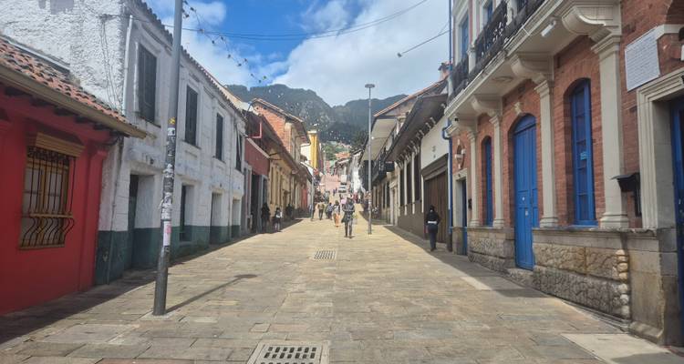 Ruelle coloniale pavée de pierre dans La Candelaria avec des maisons colorées et des montagnes vertes au loin.