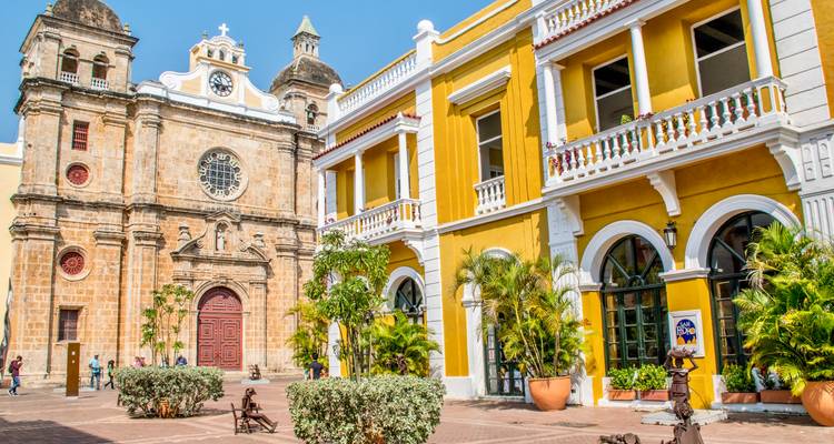Iglesia colonial amarillo brillante y edificios coloridos circundantes bajo un cielo azul despejado.