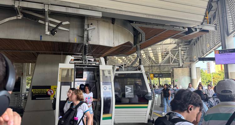 Pasajeros abordando una cabina del Metrocable dentro de la estructura de la estación elevada.