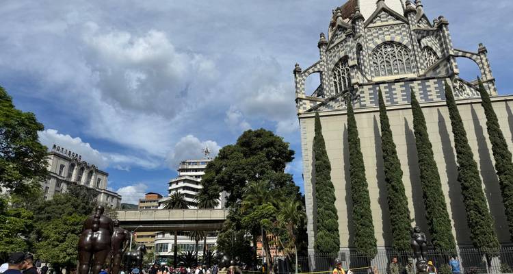 Palacio neogótico de tablero de ajedrez y altos cipreses contemplan las multitudes en la animada plaza de Medellín.