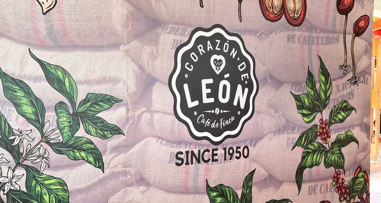 Banner ilustrado con el logo de 'Corazón de León' frente a sacos de café de arpillera apilados.