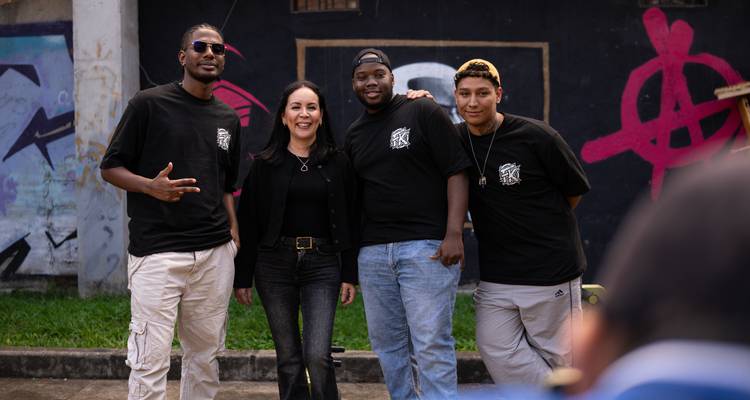 Repeat portrait of four travellers in matching black T-shirts posing in an urban setting.
