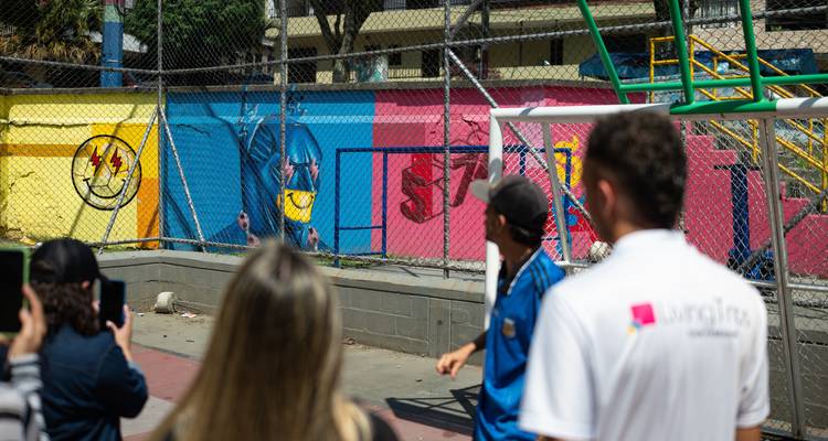 Blurred scene of visitors listening to a guide beside colorful playground walls.