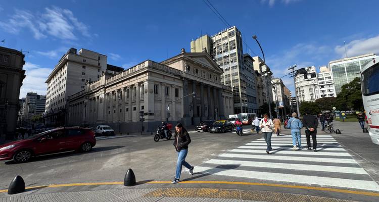 Drukke straat in Buenos Aires met historische gebouwen en verkeer onder een heldere blauwe hemel.