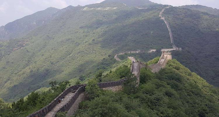Grande Muraille de Chine serpentant sur des collines vertes.
