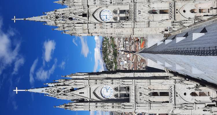 Twin neo-gothic clock towers of the Basilica del Voto Nacional rise into a crisp blue sky overlooking Quito.