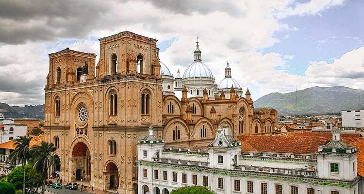 The domes and brick towers of Cuenca’s New Cathedral rise above tiled rooftops under a dramatic sky.