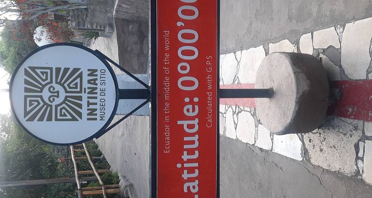 Signpost at Intiñan Museo de Sitio marks latitude 0°00'00" along the painted equatorial line.