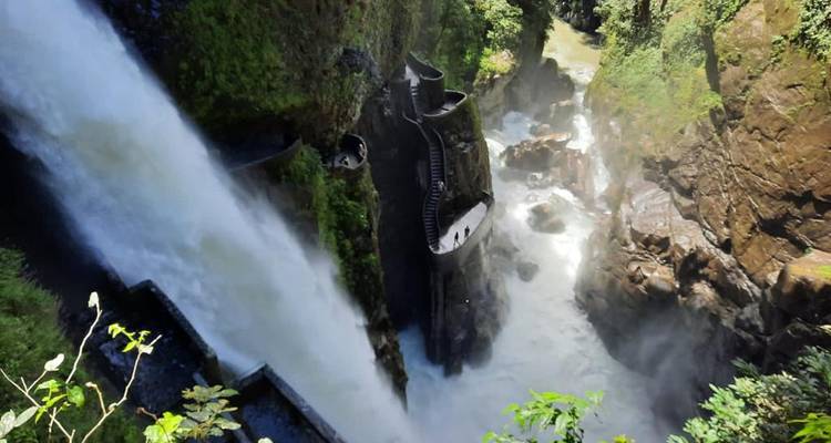 Powerful Pailón del Diablo waterfall plunges beside a dramatic cliffside staircase surrounded by mist.