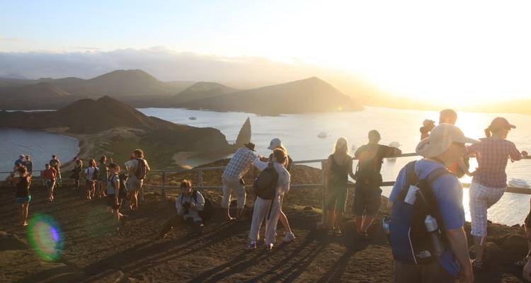 Large group of tourists admire sunset views over Bartolome Island and Pinnacle Rock in the Galapagos