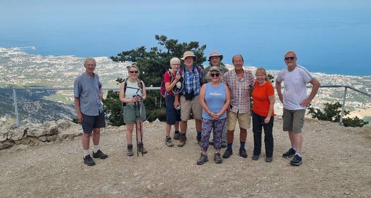 Groep wandelaars poseert bij een panoramisch uitzichtpunt hoog boven de Middellandse Zee.
