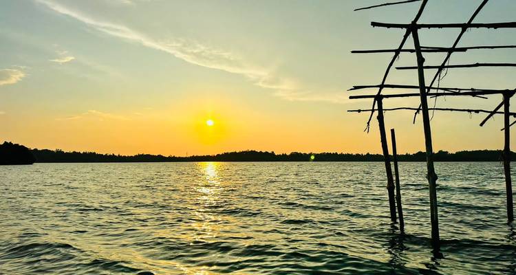 Vista del atardecer sobre un lago tranquilo con una estructura en silueta.