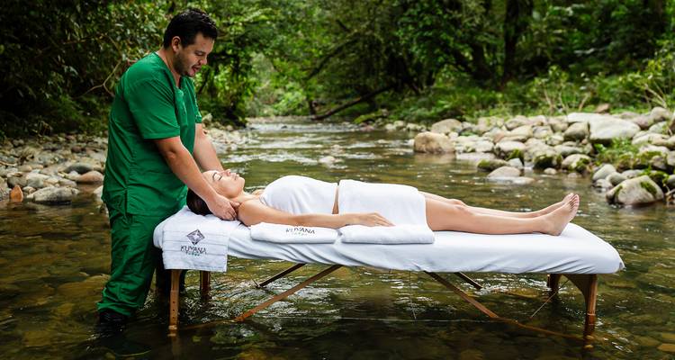 Personne recevant un massage sur une table installée dans un ruisseau.