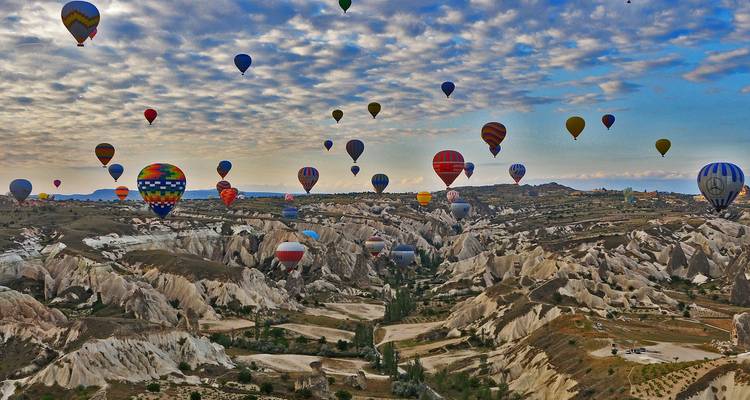 Vue large de montgolfières au-dessus de formations rocheuses.