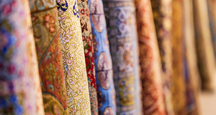 Close-up of hanging patterned fabrics in soft focus showcasing rich colours and textures.