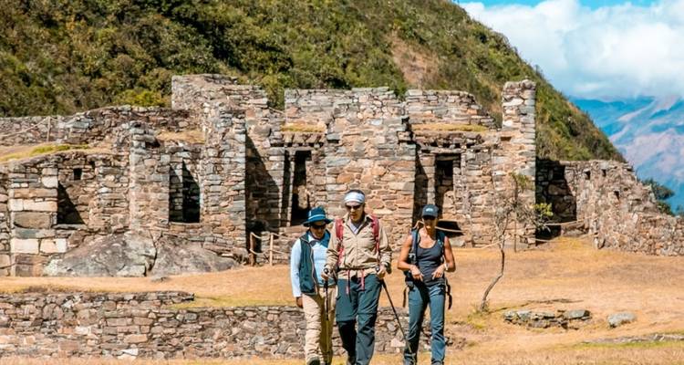 Tres personas explorando sitio arqueológico en Choquequirao.