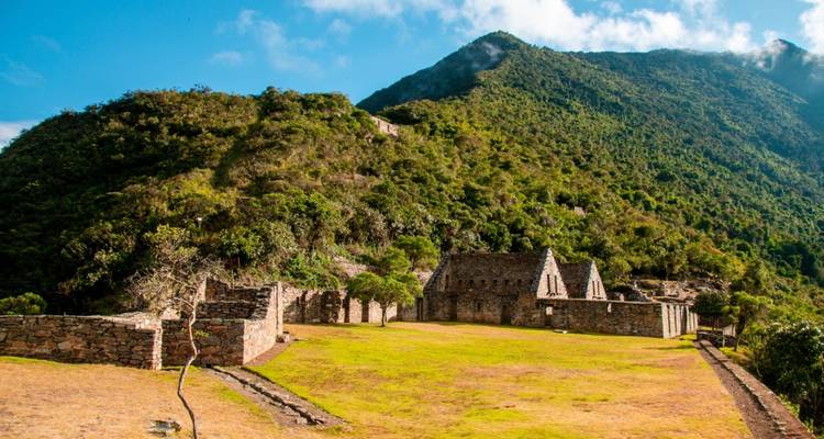 Vista amplia de las ruinas de Choquequirao y montañas distantes.