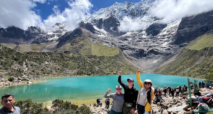 Groupe posant devant un lac turquoise et des montagnes.