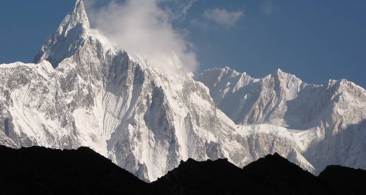 Snow-covered mountain peaks with light clouds above.