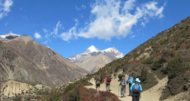 Excursionistas caminando por un sendero con paisaje de montaña.