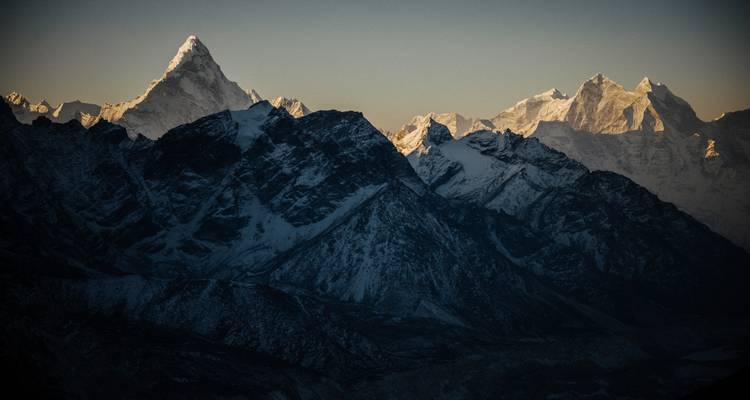 Des montagnes enneigées sous un ciel sombre.