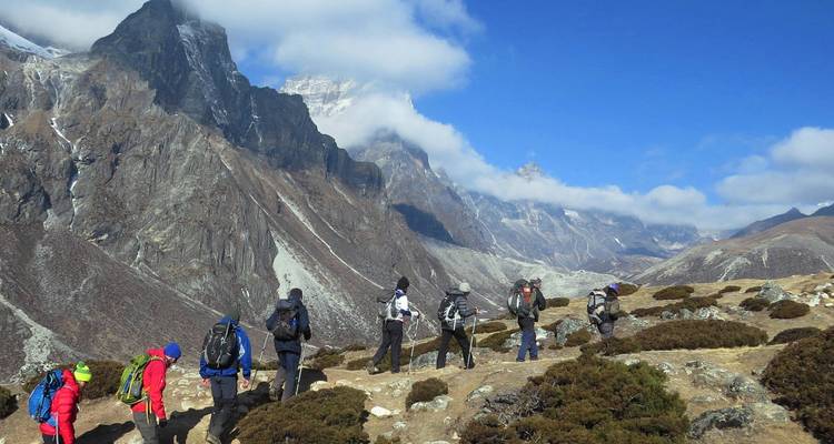 Un groupe de randonneurs sur un sentier avec de hautes montagnes en arrière-plan.