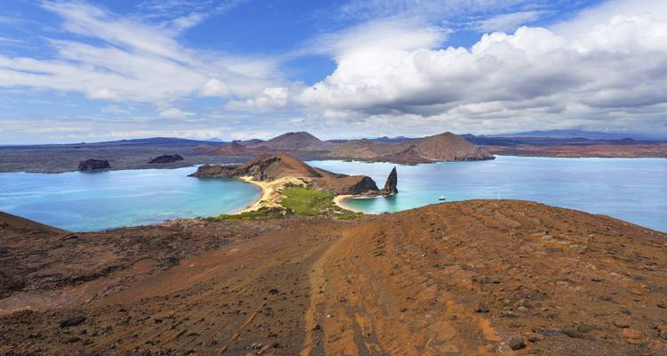 Amplia vista del paisaje marino con islas volcánicas y una playa de arena.