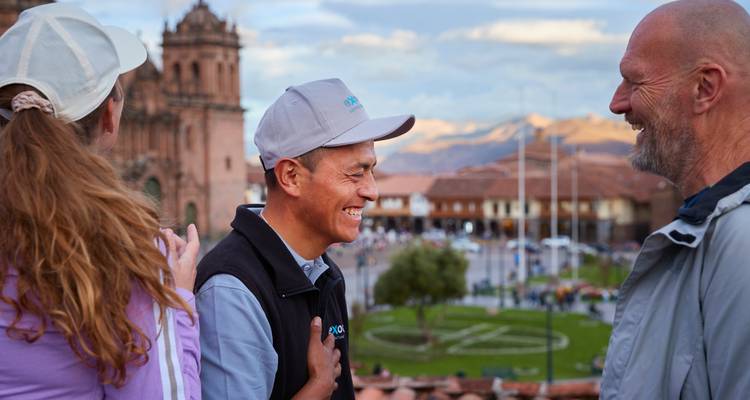 Reisende teilen ein Lachen mit einem lokalen Fremdenführer mit Blick auf den Plaza de Armas von Cusco und die Kathedrale.