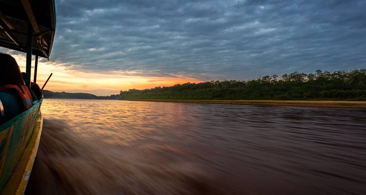 Ausblick von einem schnellen Boot entlang eines Amazonasstromes bei Dämmerung mit verschwommener Wasserbewegung.