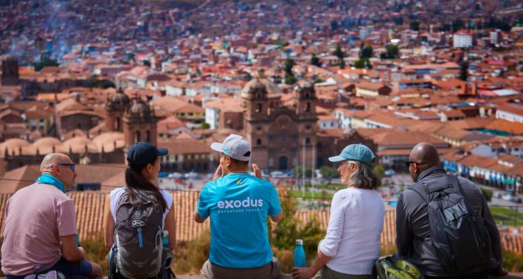 Reisende sitzen auf einer Terrasse und bewundern den Panoramablick auf die Dächer von Cusco und die Kathedrale.
