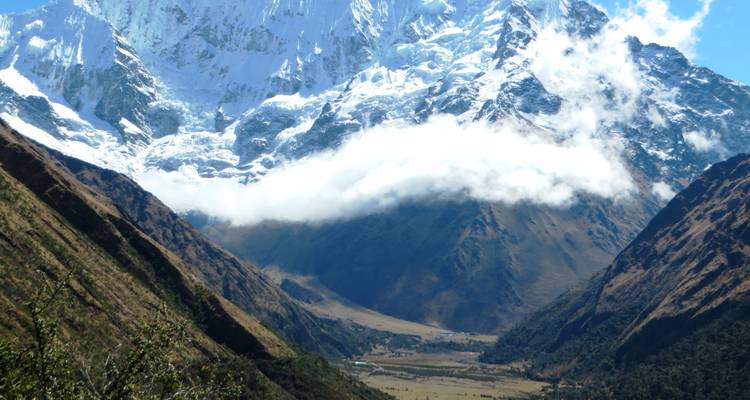 Valle con montañas nevadas y cielo nublado.