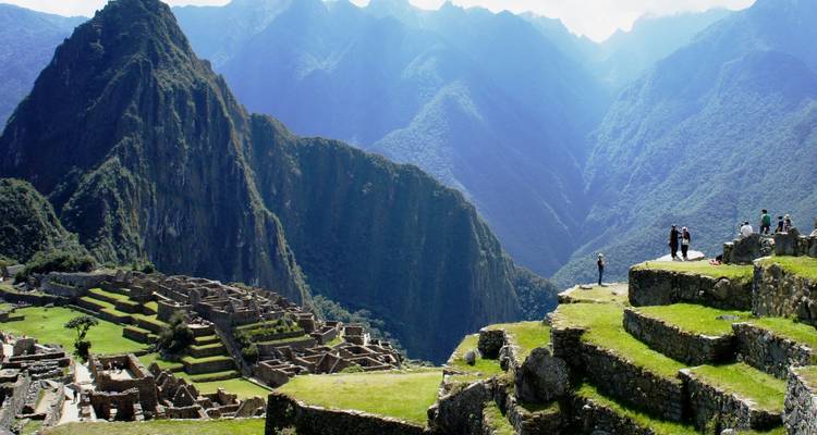 Turistas en Machu Picchu con montañas al fondo.