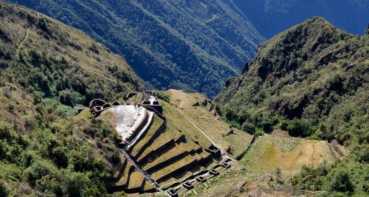 Vista panorámica de las ruinas incas en un valle rodeado de exuberantes montañas verdes.