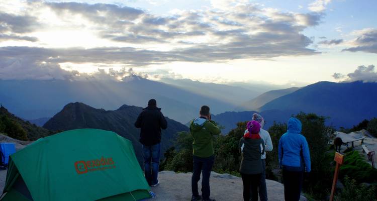Groupe de personnes en train de camper avec une vue pittoresque sur les montagnes au coucher du soleil.