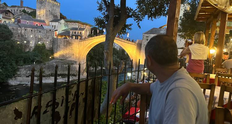 Restaurantgäste blicken bei Einbruch der Dunkelheit auf die beleuchtete Stari-Most-Brücke, die sich über den Fluss in Mostar erstreckt.