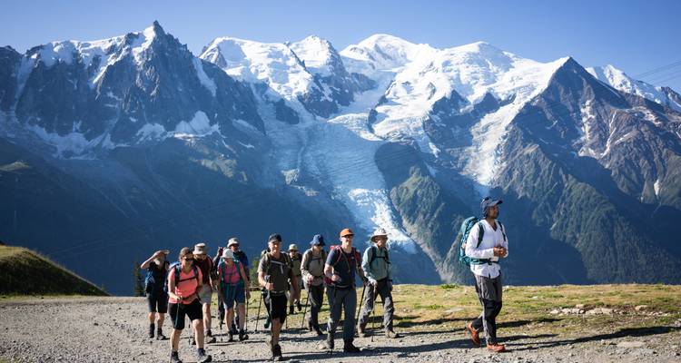 Groupe de randonneurs marchant avec des montagnes enneigées en arrière-plan.
