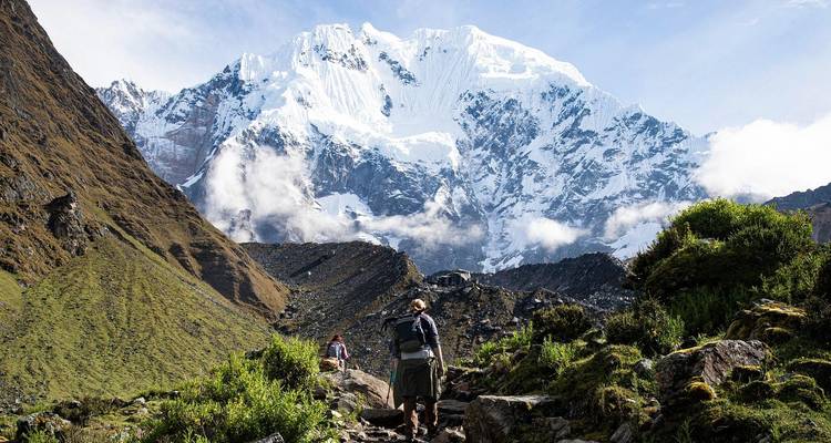 Hikers ascend a stone path toward the towering snow-capped Salkantay peak.